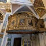 Sulla destra troviamo una raffinata cantoria in legno, decorata con riquadri di santi...